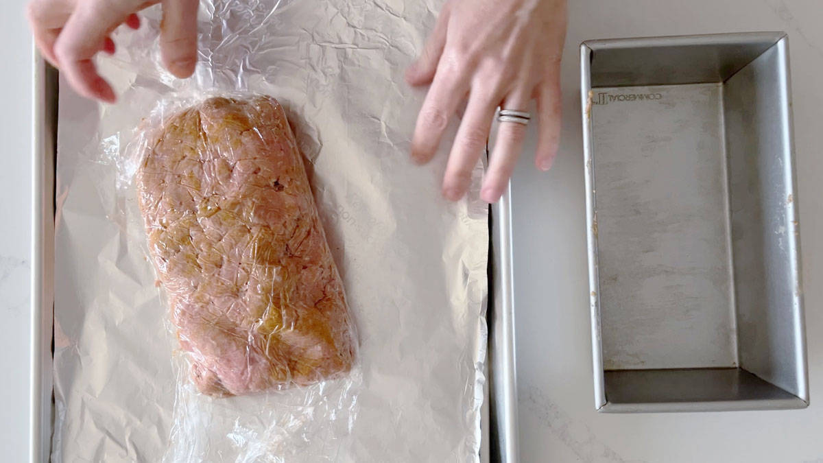 Removing the cling wrap from the meatloaf.