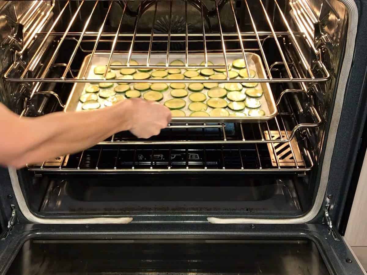 Placing the zucchini chips in the oven.