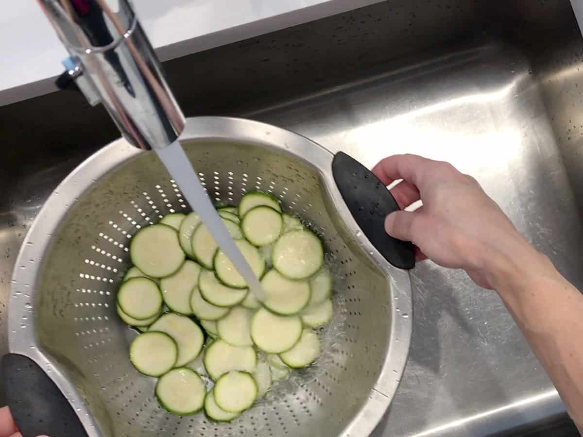 Rinsing the zucchini slices.