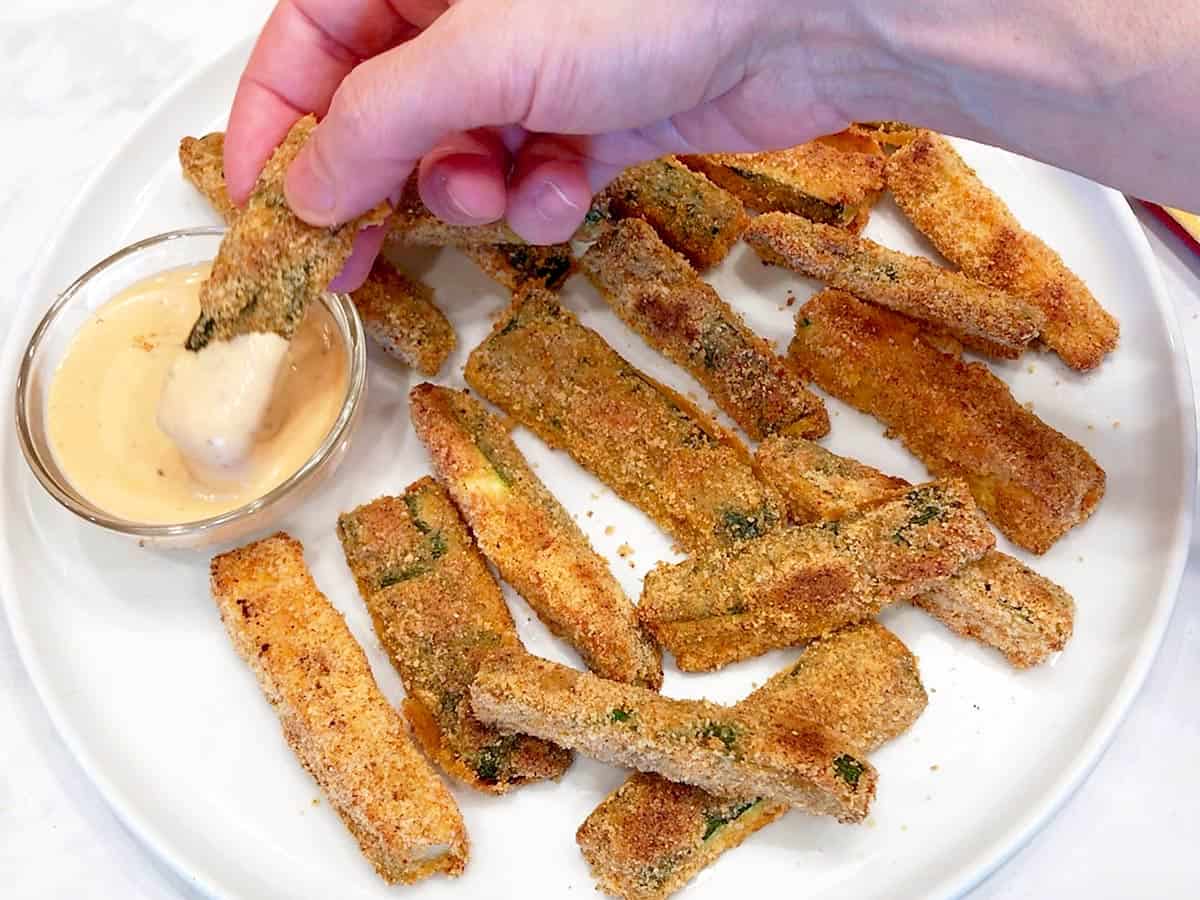 Dipping a zucchini fry in a dipping sauce.