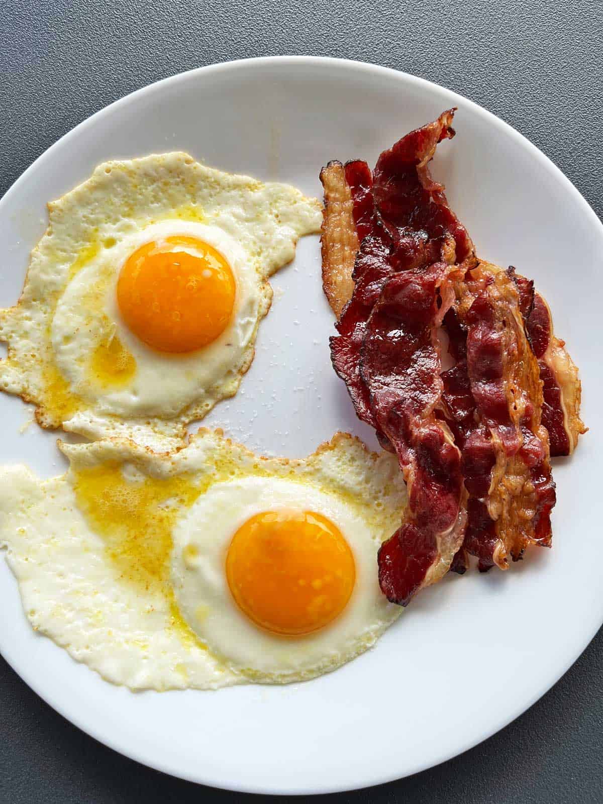 Beef bacon is served with fried eggs.
