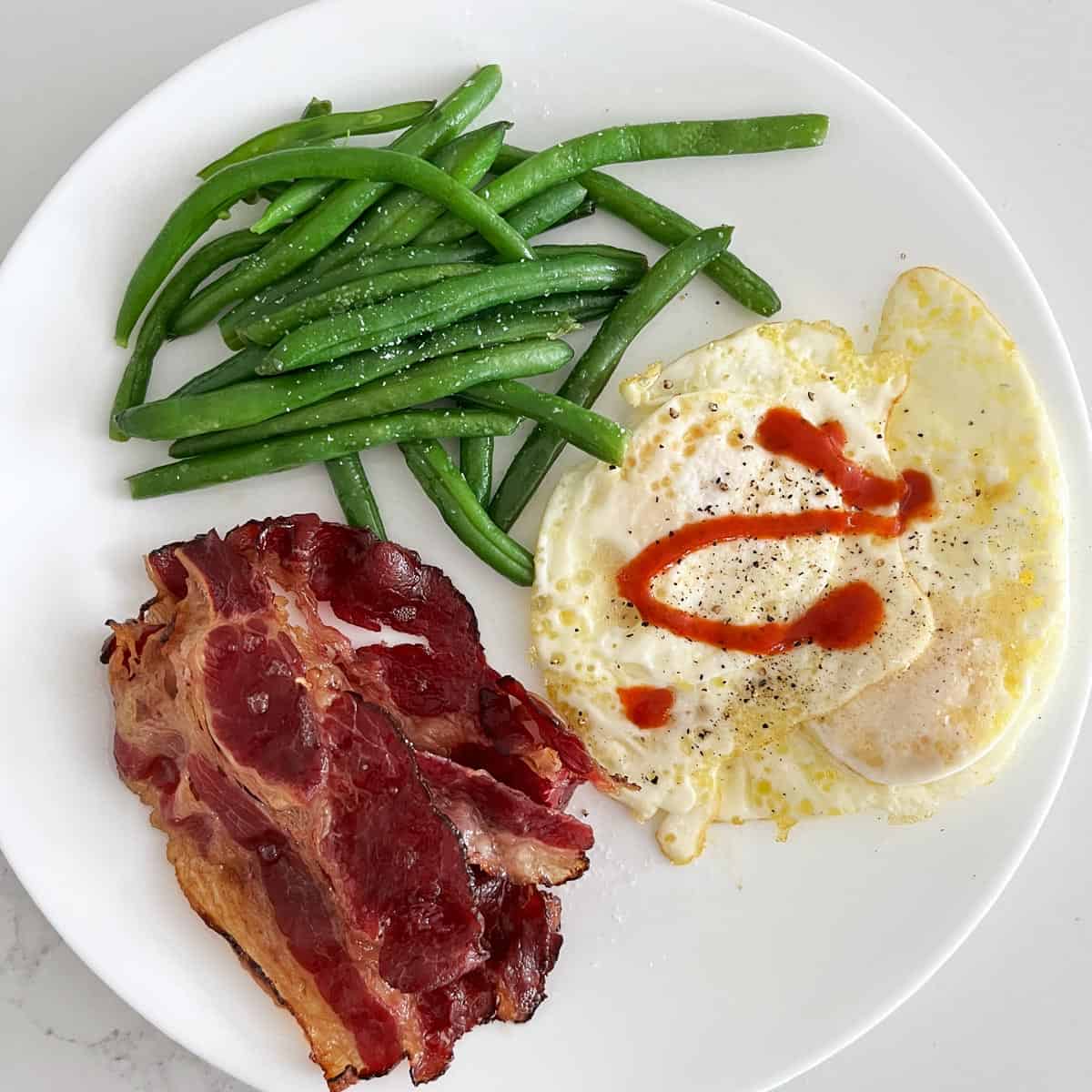 Beef bacon served with fries egg (over hard) and green beans.