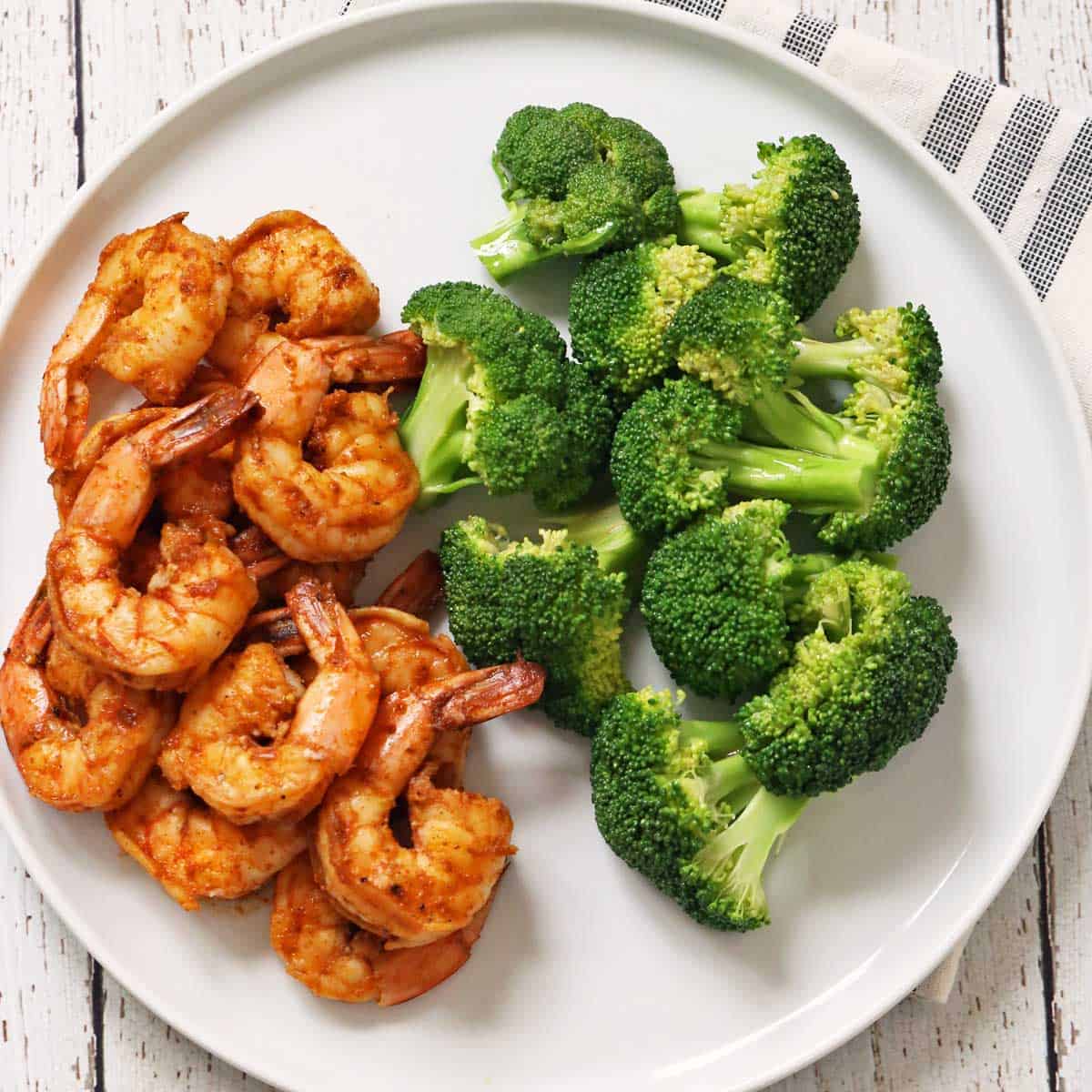 Steamed broccoli is served with sauteed shrimp.