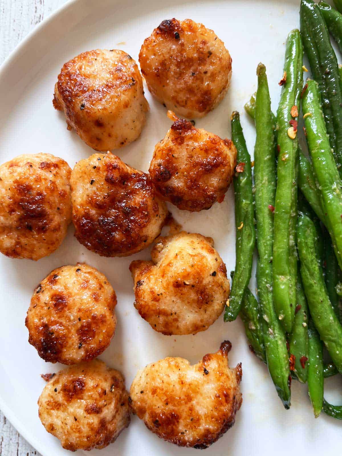 Broiled scallops are served with green beans.