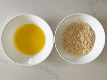 A bowl with melted butter and a bowl of seasoned parmesan.