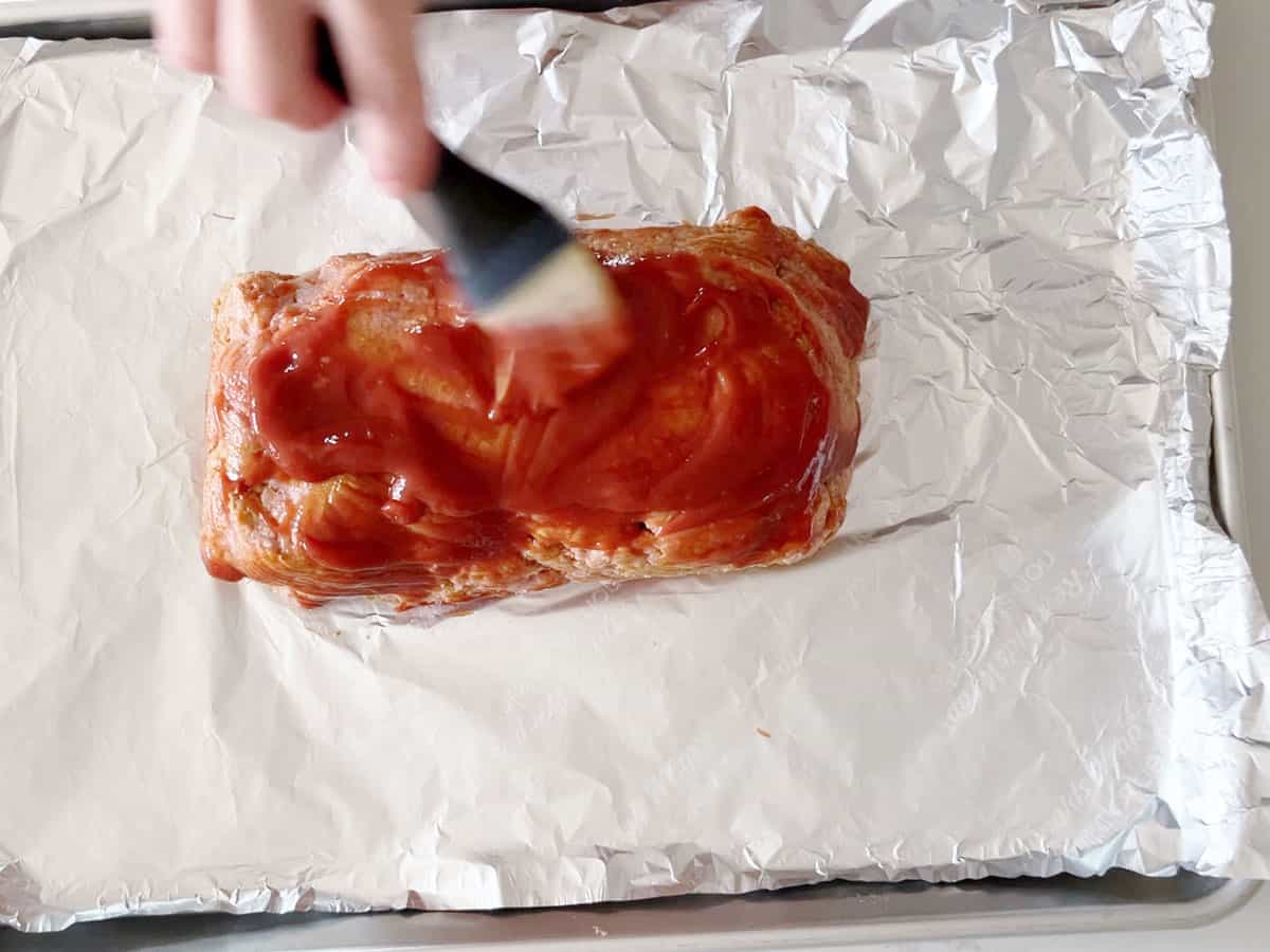 Brushing the meatloaf with ketchup before baking it.