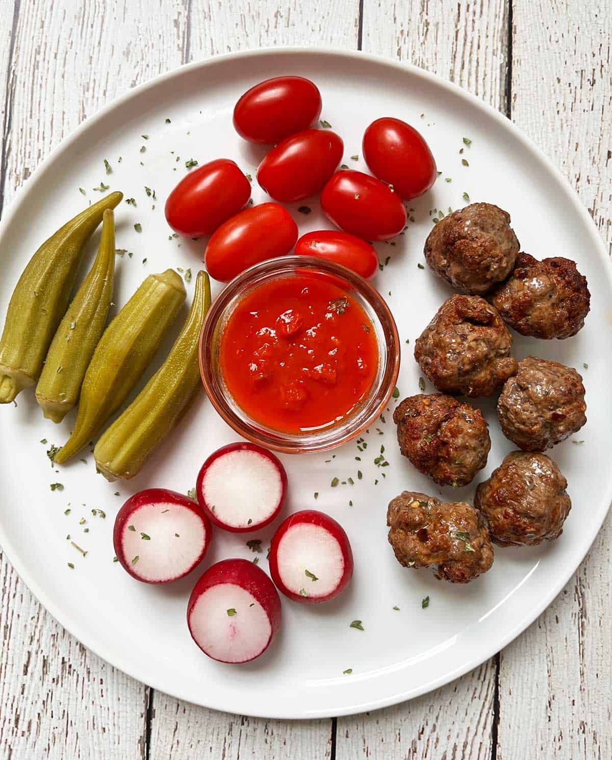 Leftover keto meatballs are served with veggies, pickles, and a dip.