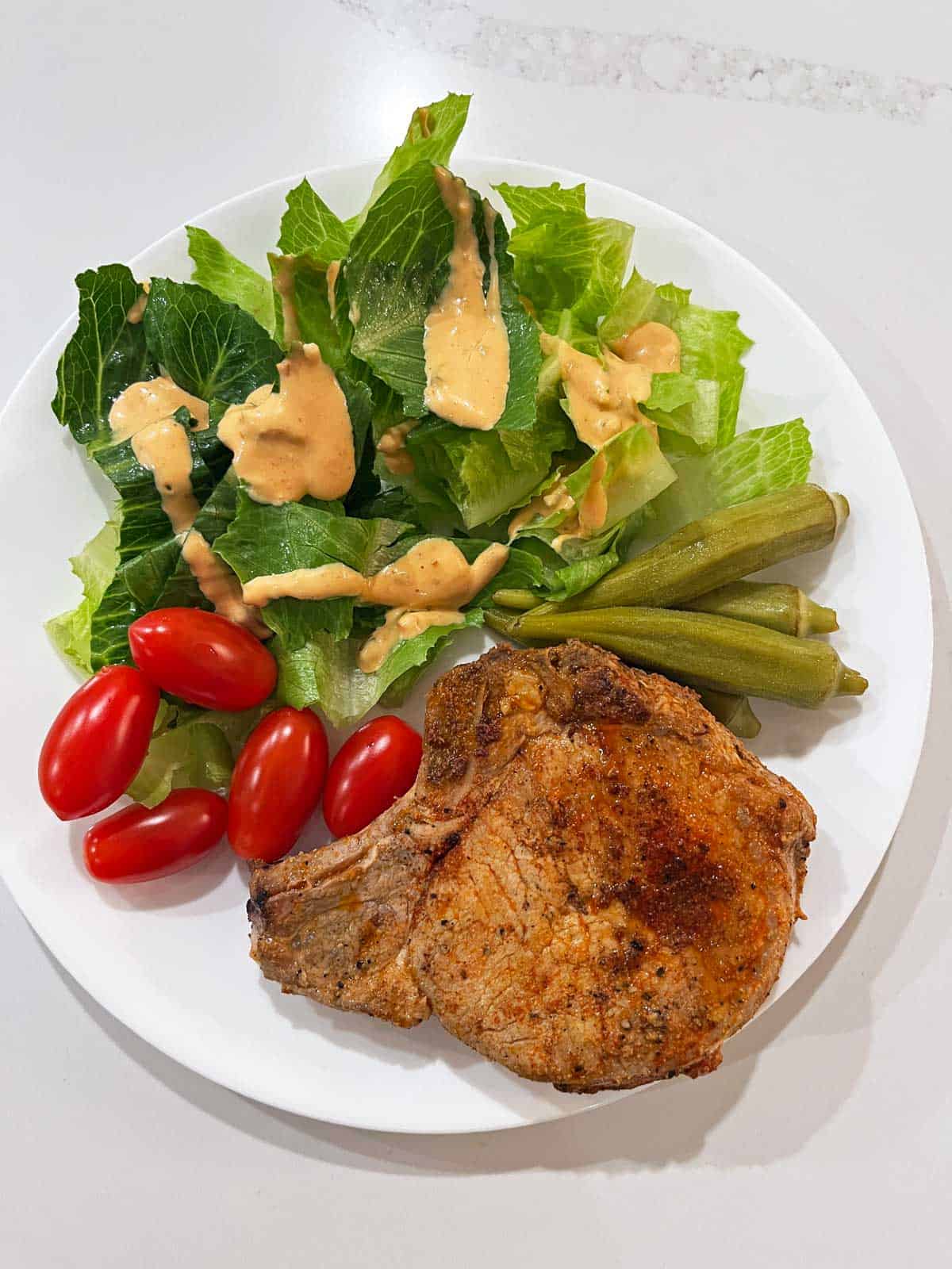 A leftover pork chop is served with a simple side salad.