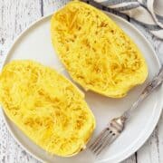 Microwave spaghetti squash is served on a white plate with a fork.