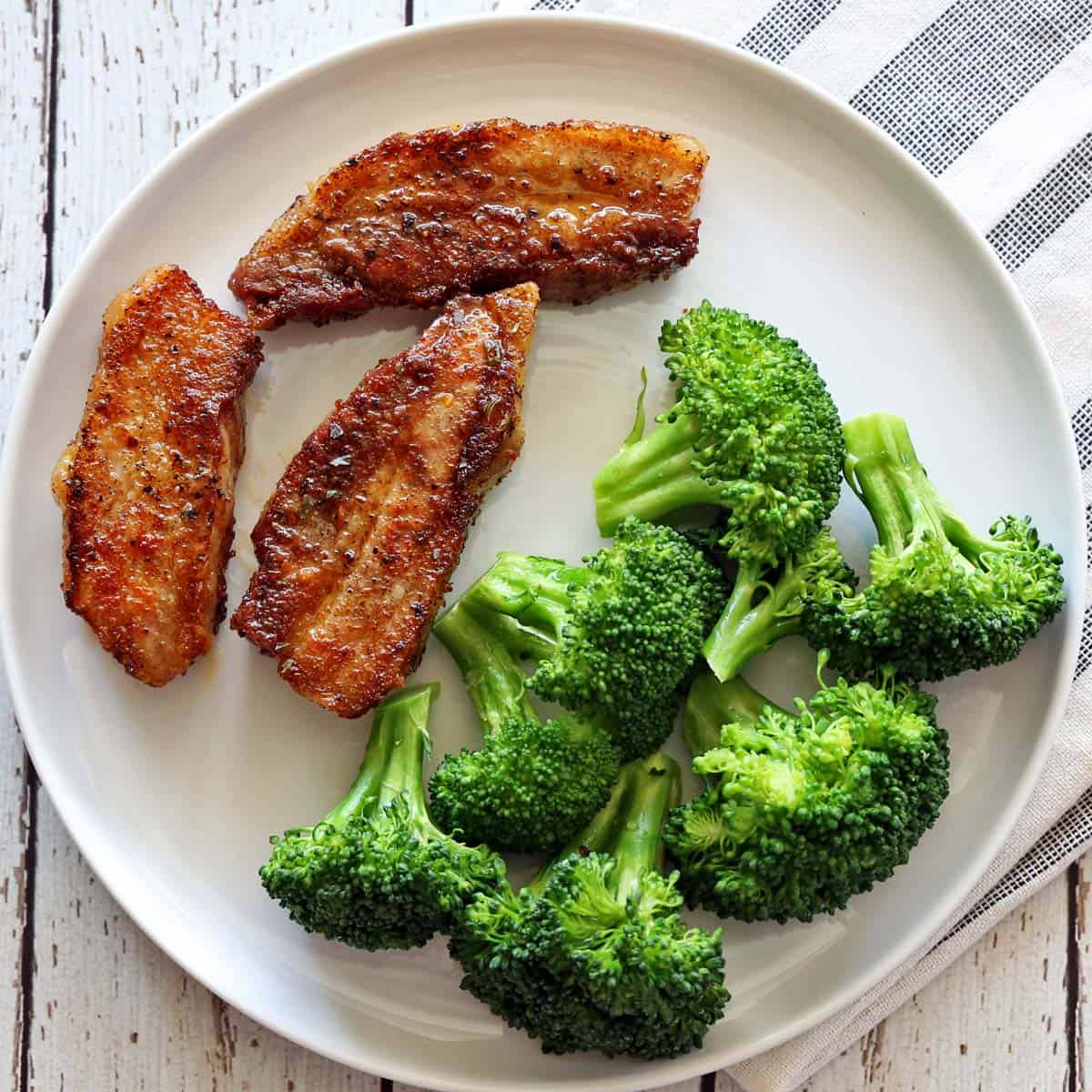 Pork belly is served with broccoli for dinner.