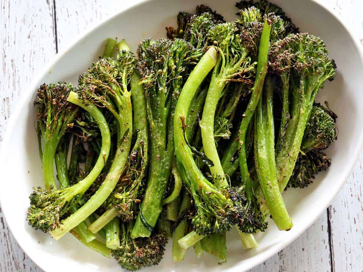 Roasted broccolini is served on a white platter.