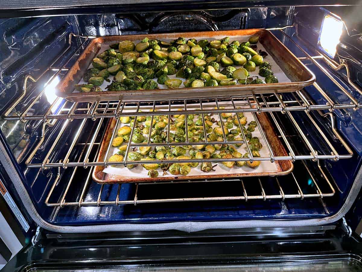 Two sheet pans of Brussels sprouts roasting simultaneously.