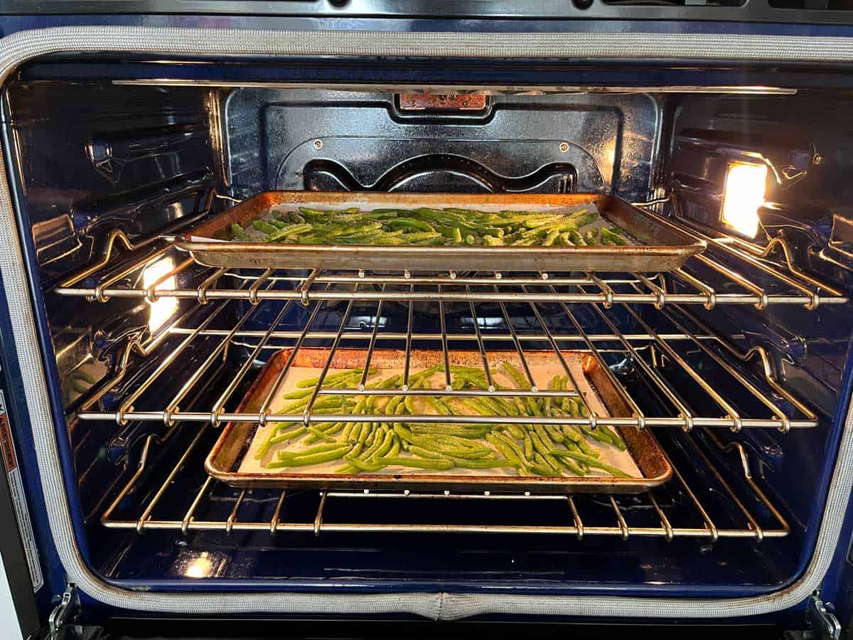 Two pans of green beans in the oven.