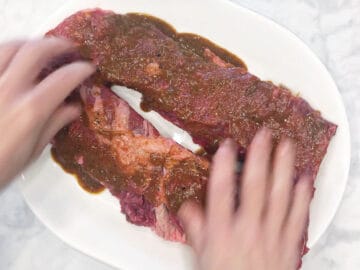 Rubbing the marinade into the steak.