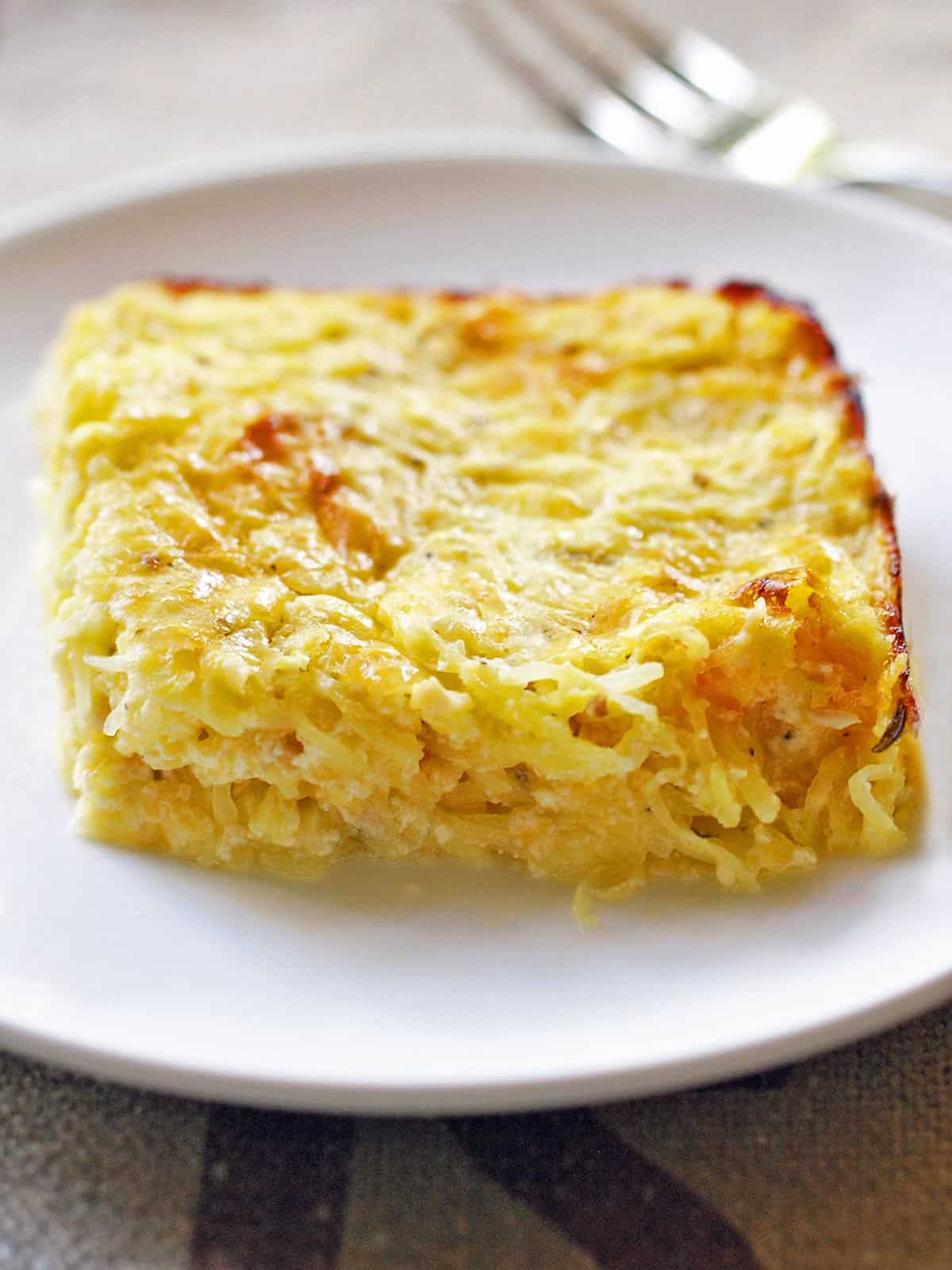 A slice of spaghetti squash casserole is served on a white plate.