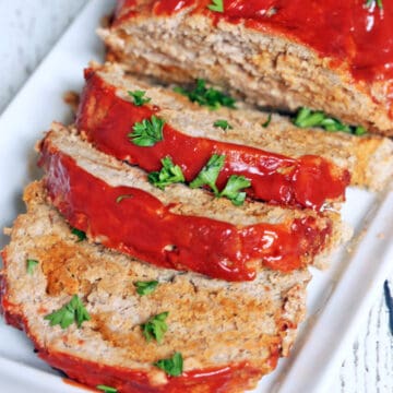 A turkey meatloaf is topped with chopped parsley.