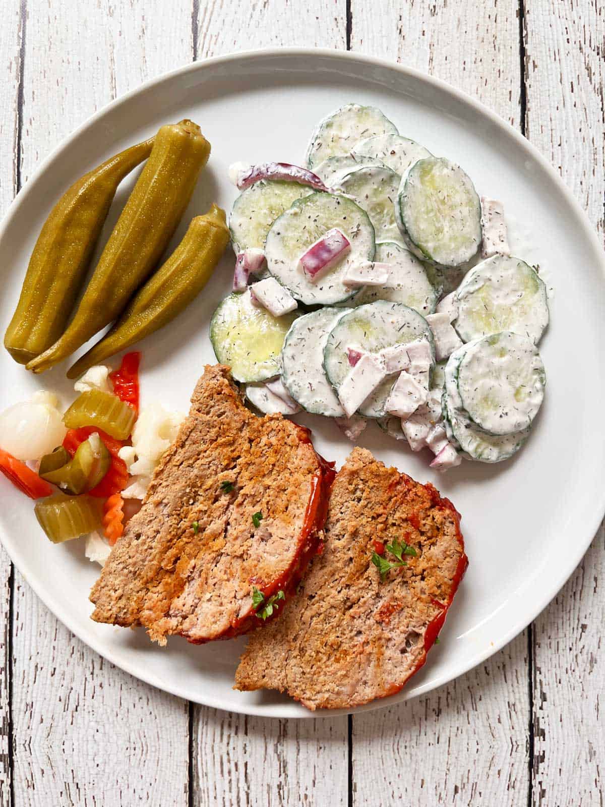 Turkey meatloaf is served with a cucumber salad and pickles.
