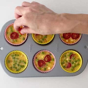 Adding tomatoes to the egg muffins.