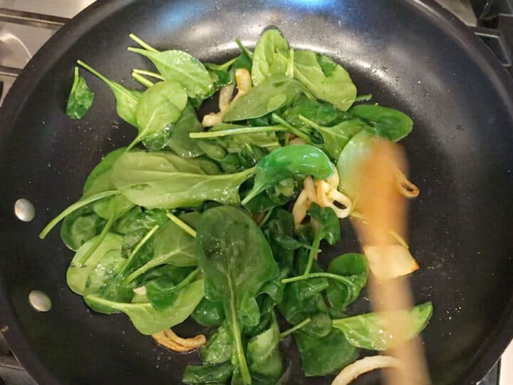 Adding spinach to the skillet.