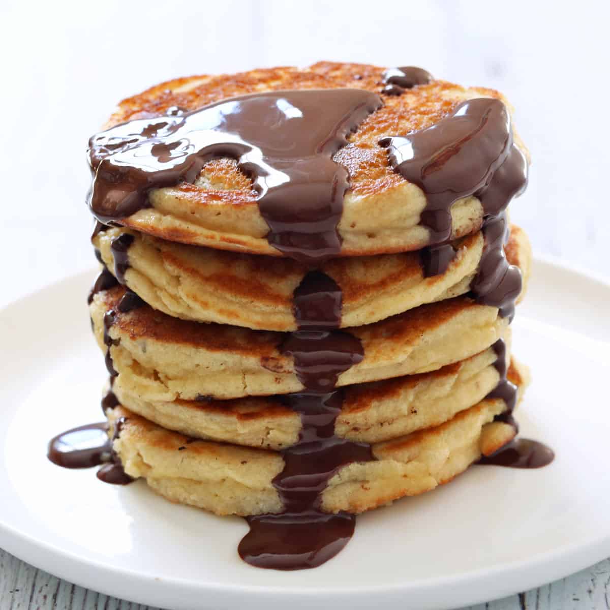 Almond flour pancakes are topped with melted chocolate.