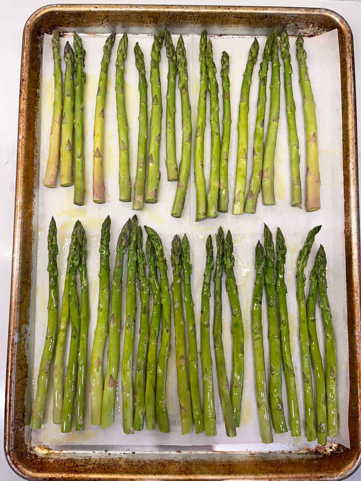 Asparagus spears are coated in olive oil.