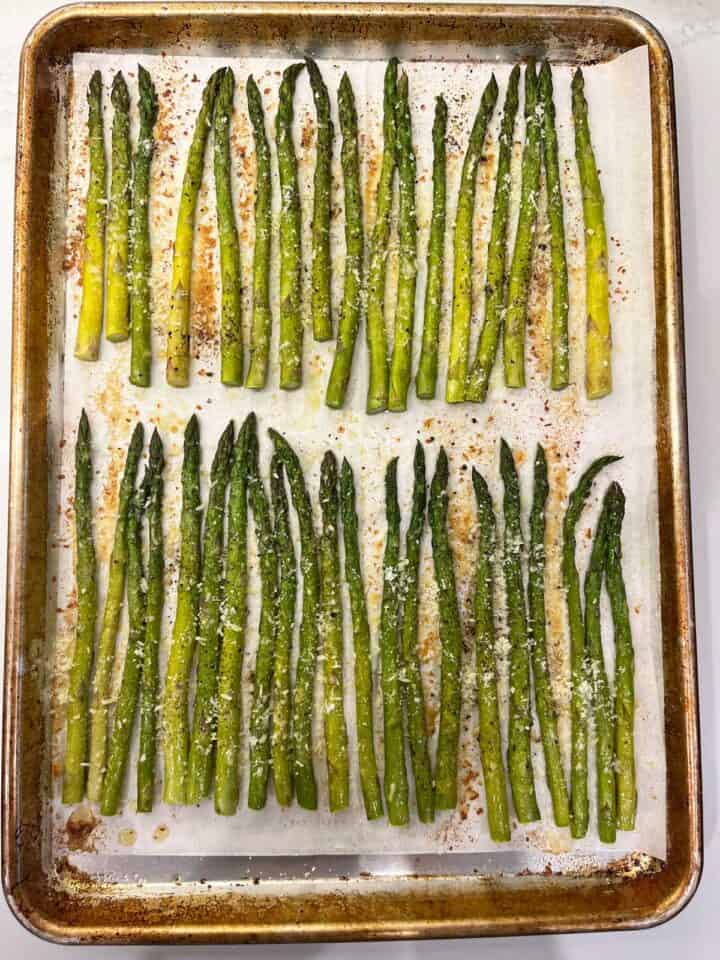 Sprinkling parmesan on the cooked asparagus.