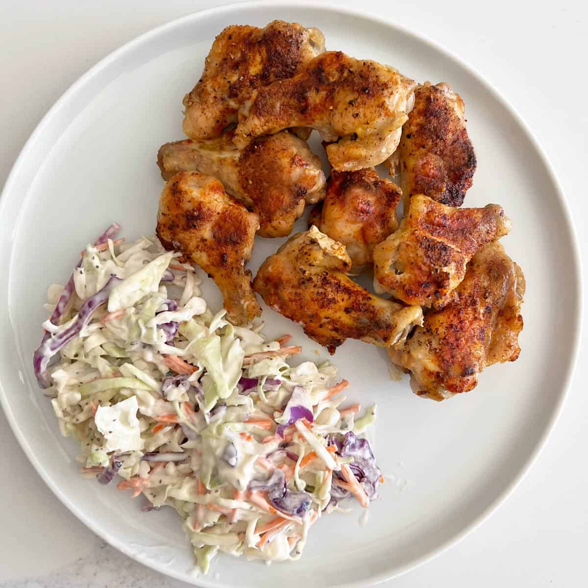 Baked chicken wings are served with coleslaw.