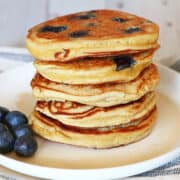 Coconut flour pancakes are served with fresh blueberries.