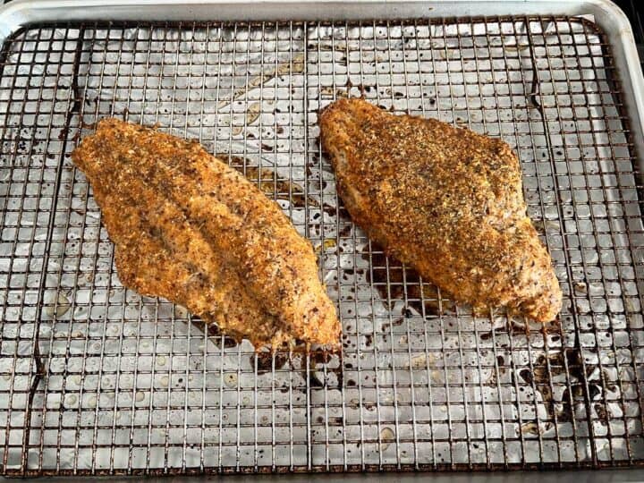 Two baked catfish fillets are ready in the pan.