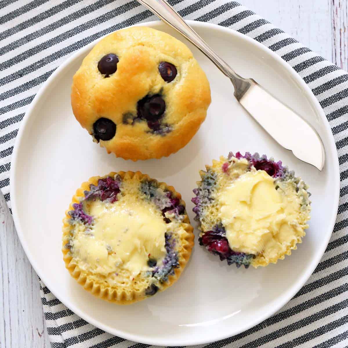 Topping keto blueberry muffins with butter.