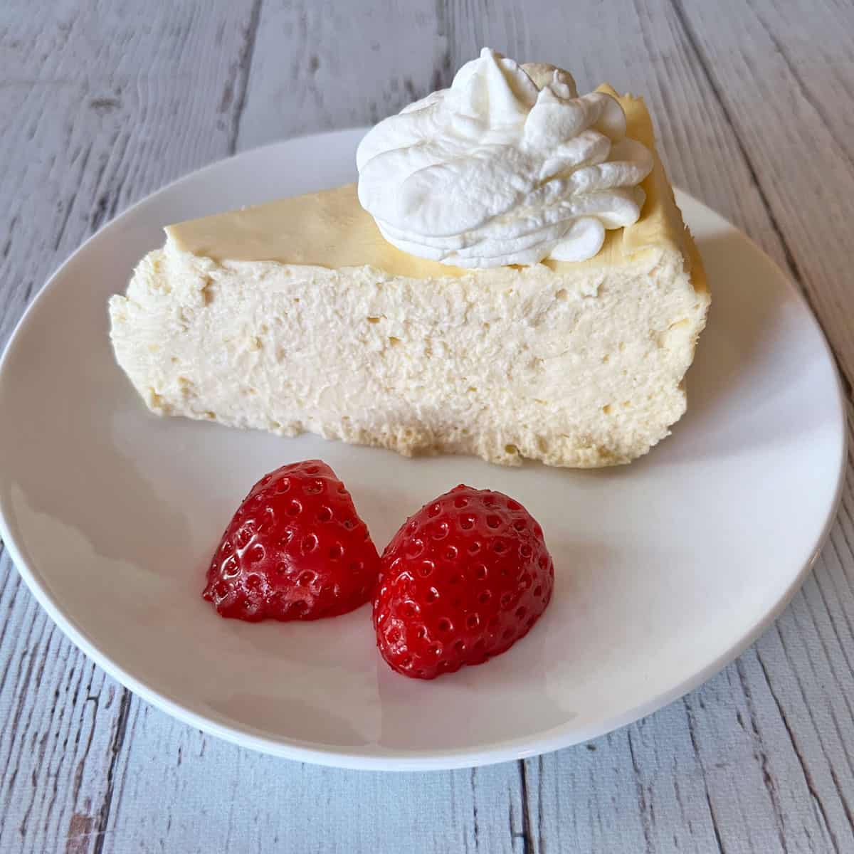 A slice of keto cheesecake is topped with keto whipped cream.