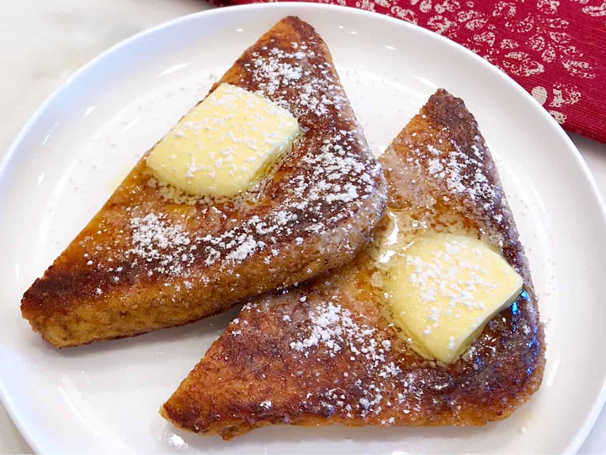 Keto French toast is served on a white plate, topped with butter.