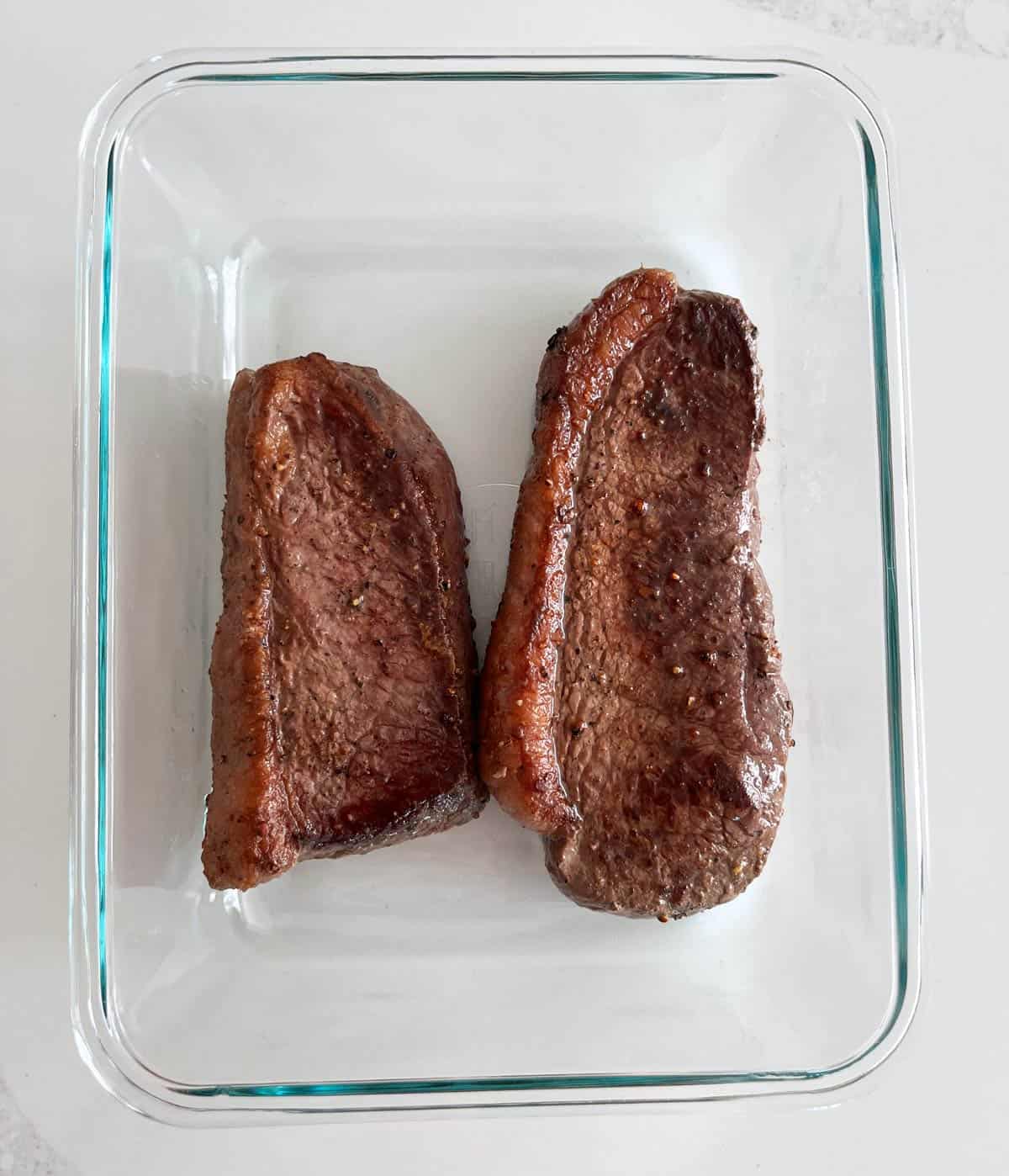 Picanha steak leftovers are stored in a glass food storage container.