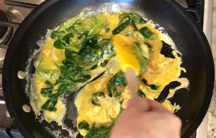 Pushing the eggs back and forth in the skillet.
