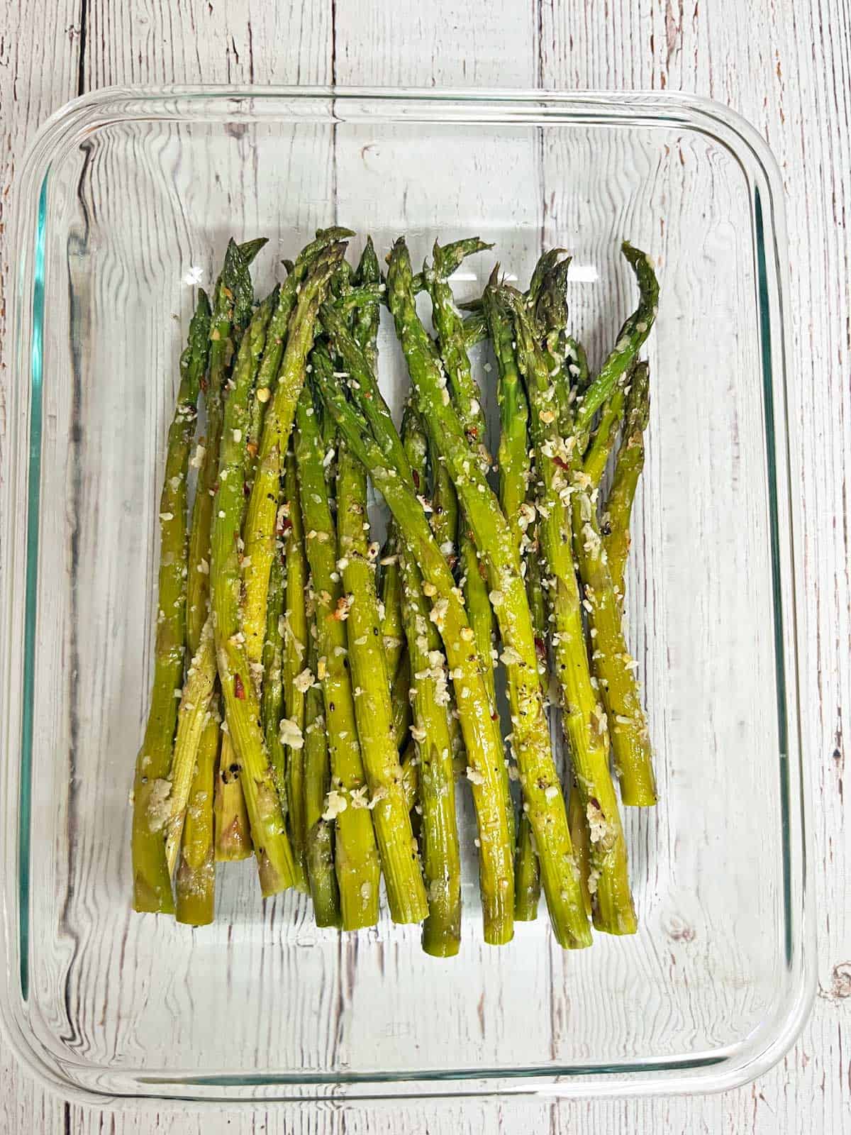 Roasted asparagus leftovers are stored in a glass food storage container.