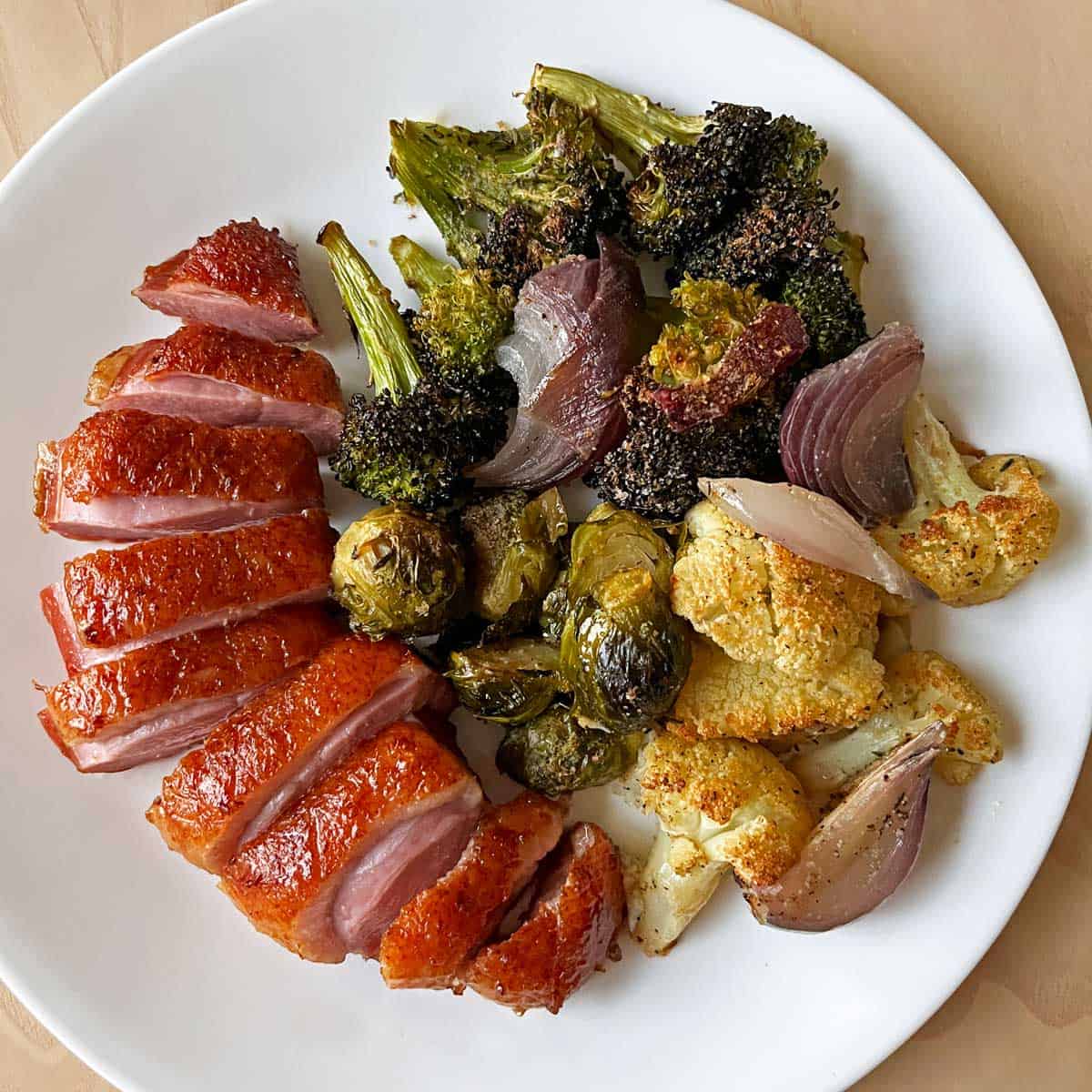 Roasted vegetables are served with duck breast.