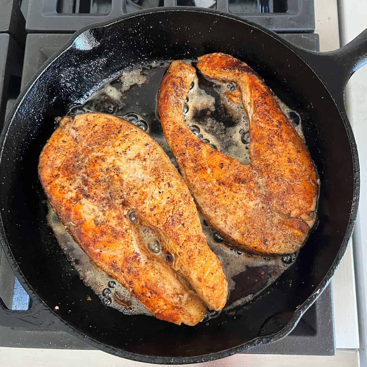 Two salmon steaks in the pan after they were flipped.