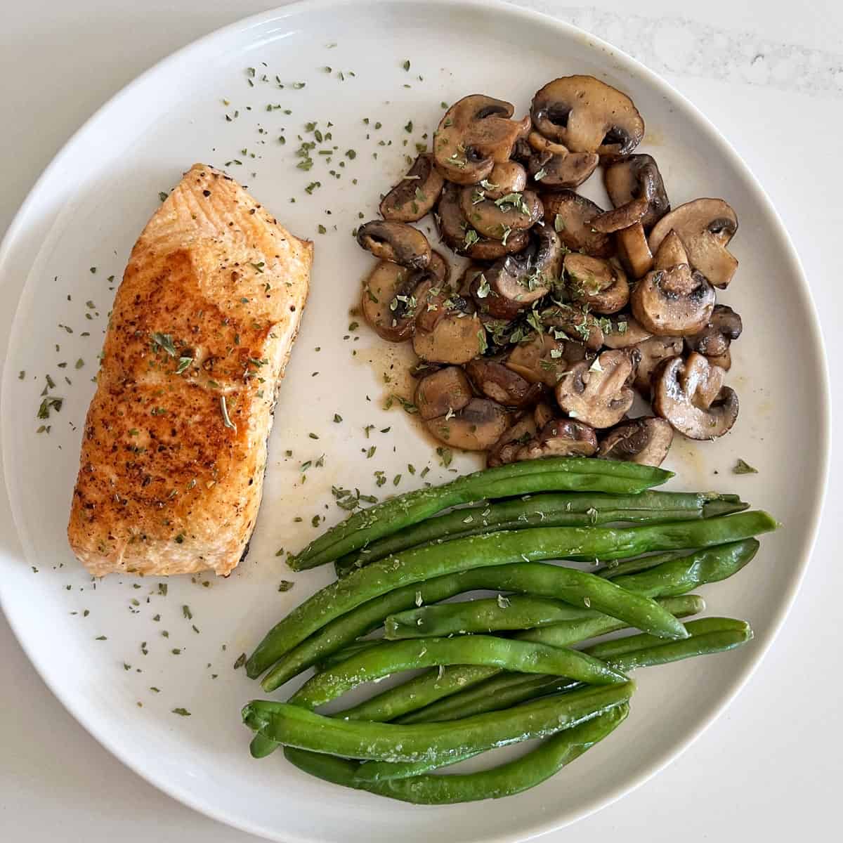 Sauteed mushrooms are served with green beans and salmon.