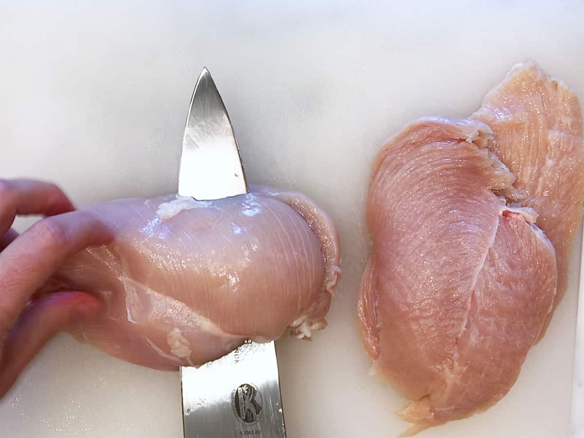 Slicing the raw chicken breasts.