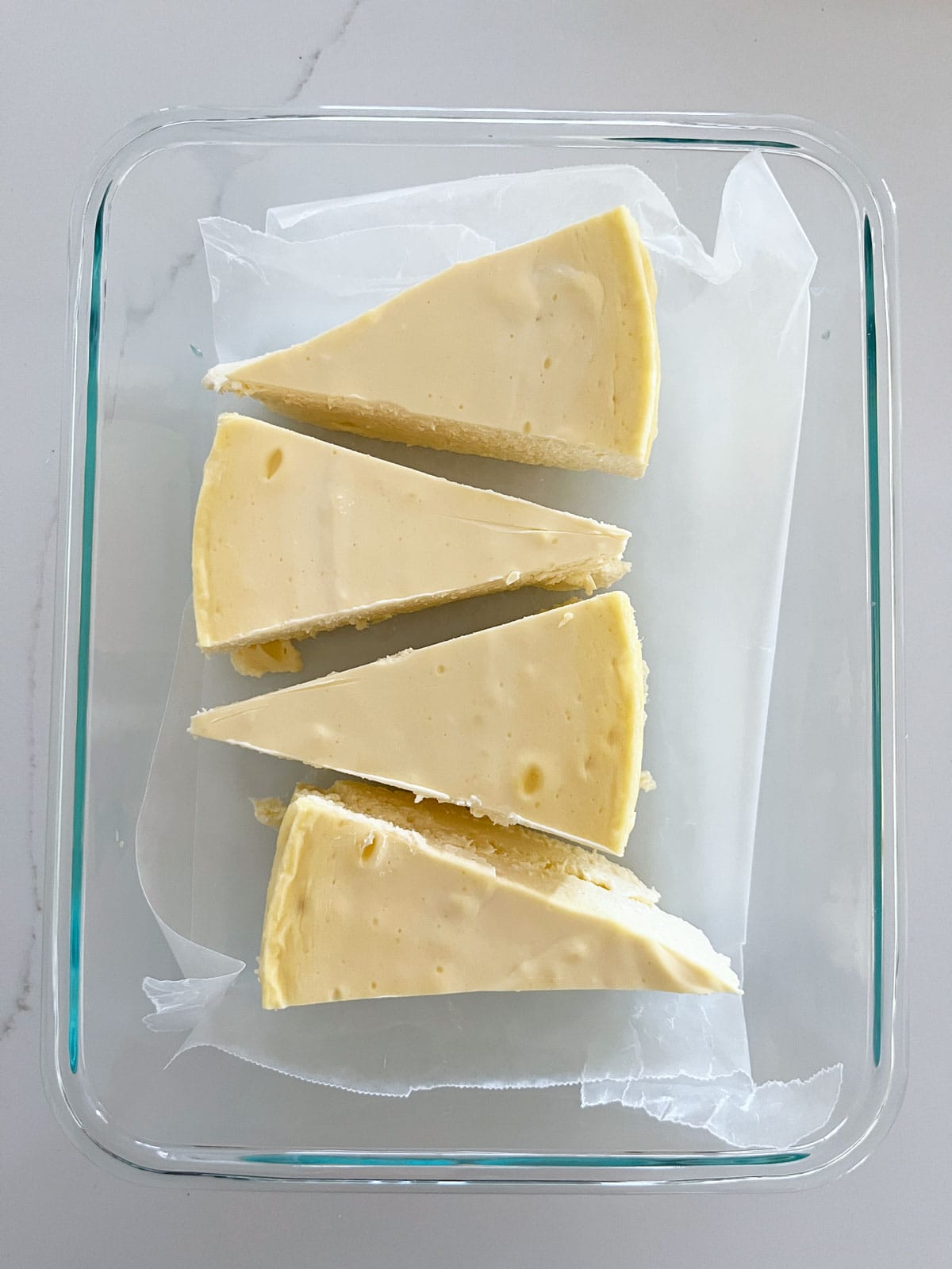 Keto cheesecake slices are stored in a glass food storage container.