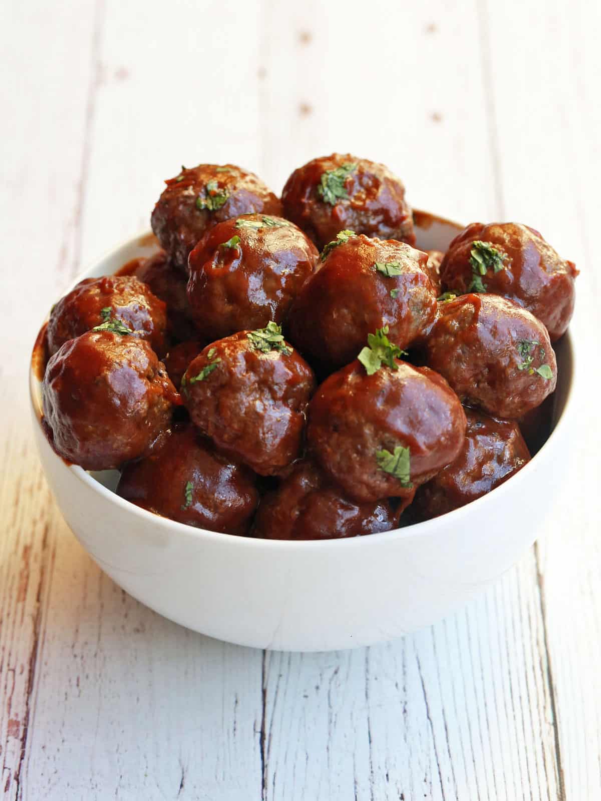 Sweet and sour meatballs are served in a white bowl.