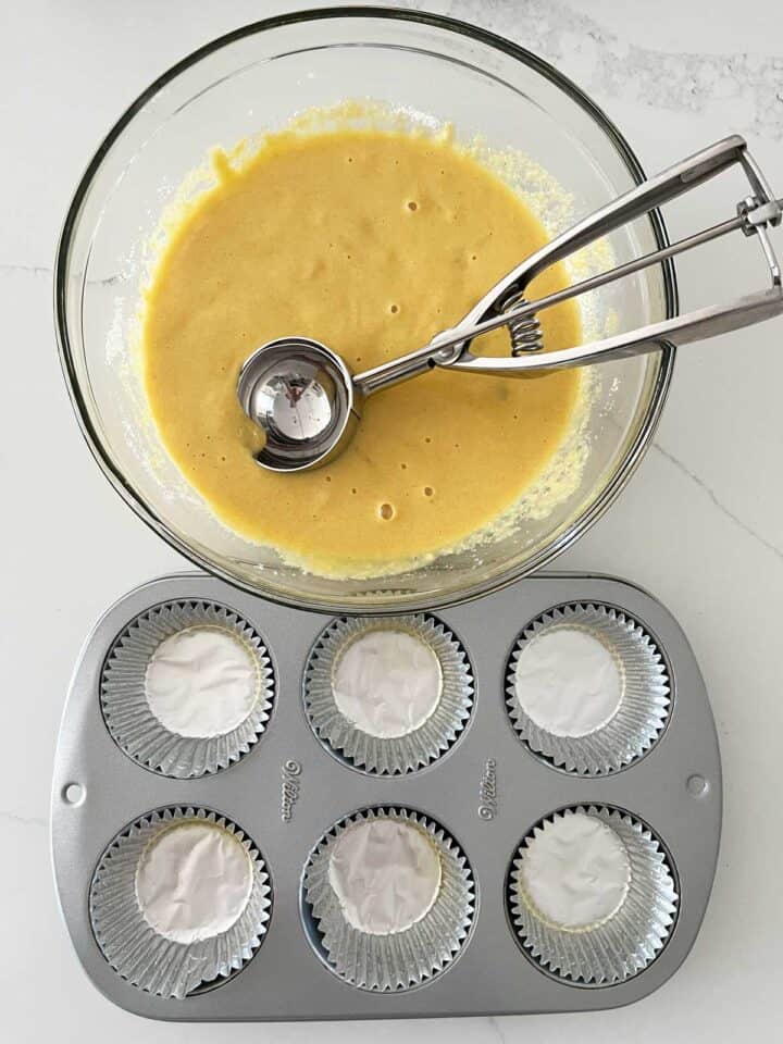 Using a scoop to transfer the batter to the muffin pan.