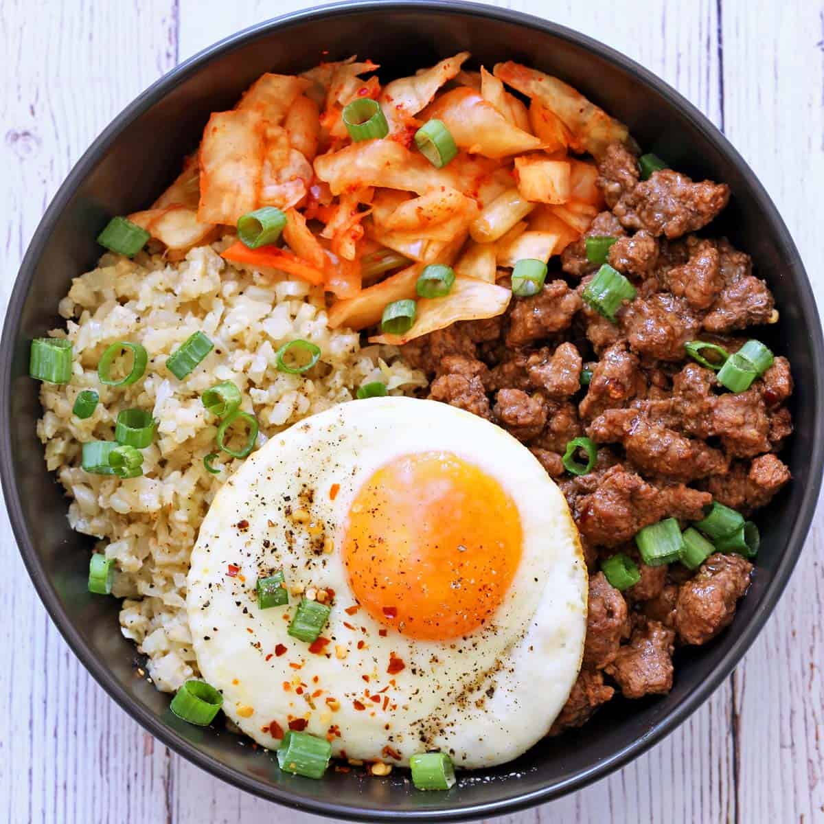 A serving suggestion for Korean ground beef: serve it in a bowl with cauliflower rice, kimchi, a fried egg, and scallions.