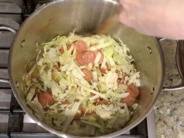 Adding the cabbage to the pot.