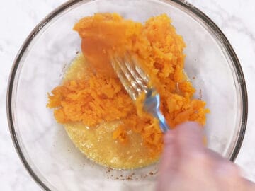 Mixing the mashed sweet potato into the melted creamy ingredients in a bowl.