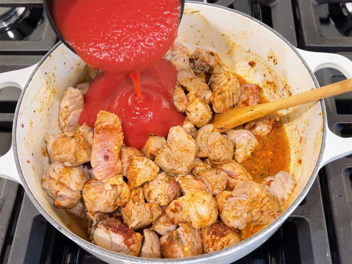 Adding tomato sauce to the stew.