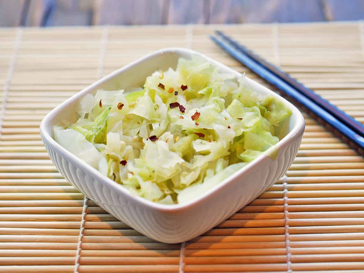 Asian-style steamed cabbage is served with chopsticks.