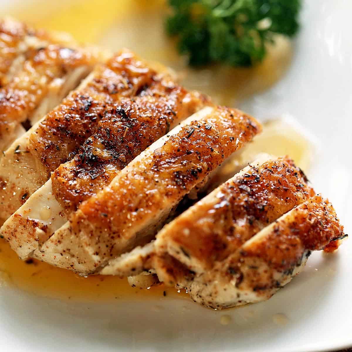 Sliced skin-on chicken breast on a white plate.