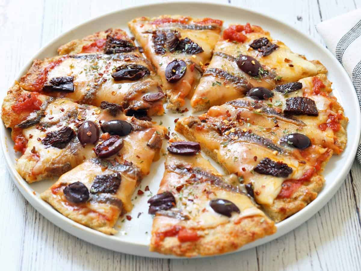 A chicken crust pizza topped with anchovies, olives, and sun-dried tomatoes.