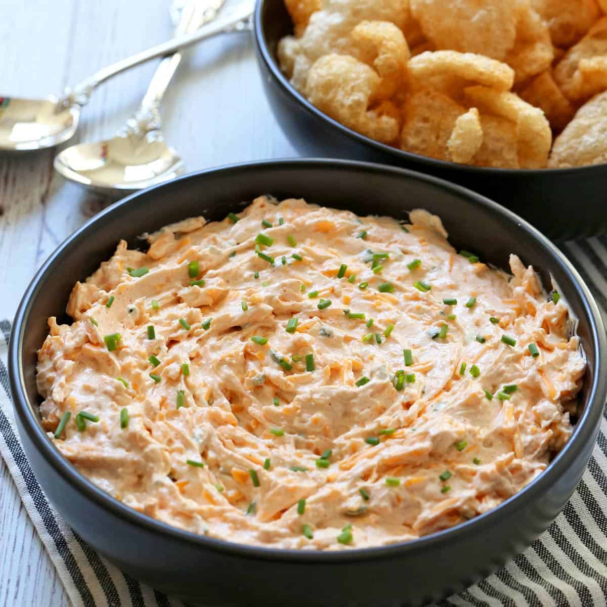 Cream cheese dip is served in a bowl with pork rinds for scooping.